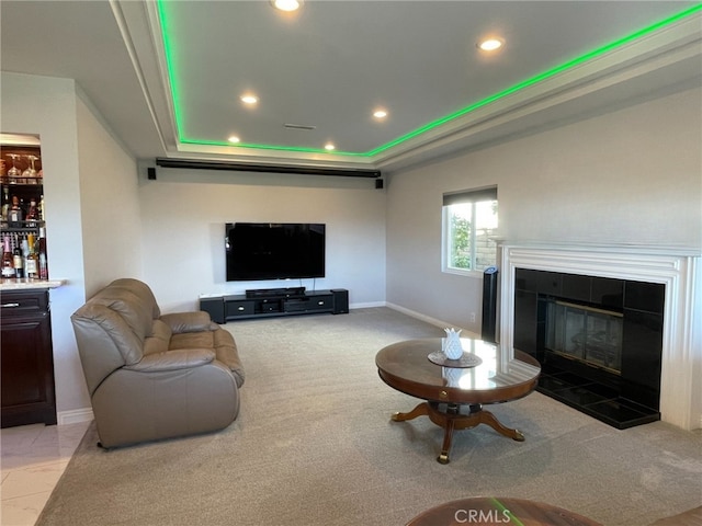 living area featuring baseboards, a raised ceiling, a tile fireplace, light colored carpet, and recessed lighting