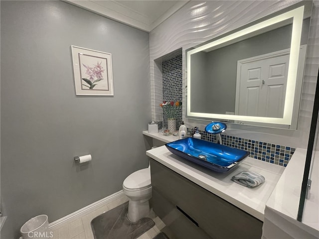 bathroom featuring baseboards, backsplash, toilet, and vanity