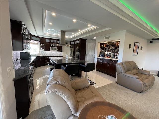 living room featuring visible vents, a tray ceiling, a dry bar, and recessed lighting