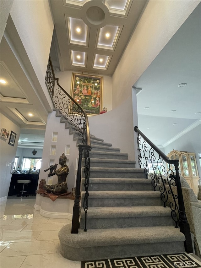 staircase featuring crown molding, marble finish floor, a high ceiling, and baseboards