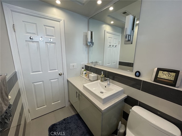 half bathroom featuring recessed lighting, visible vents, vanity, and toilet