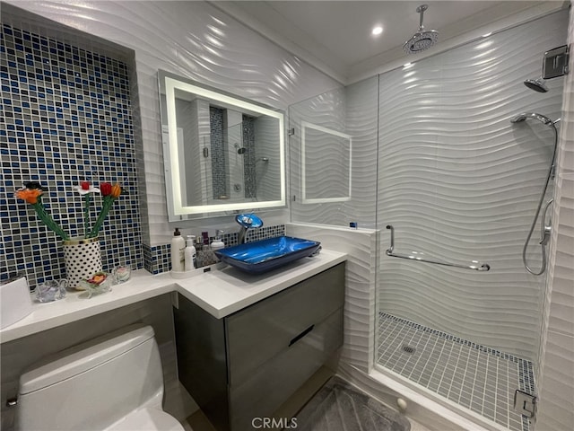 bathroom featuring tile walls, backsplash, toilet, a shower stall, and vanity