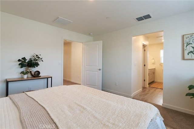 bedroom with ensuite bath, baseboards, and visible vents