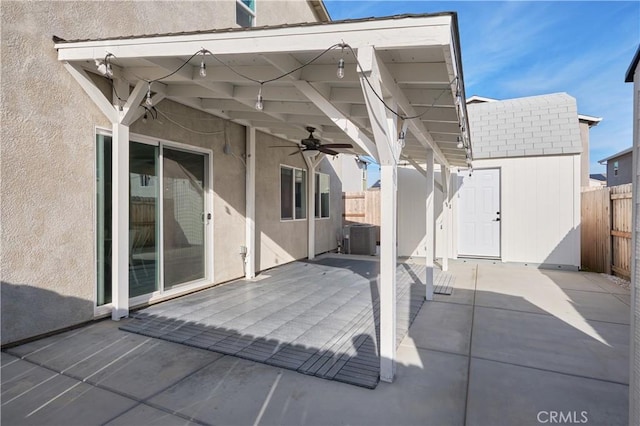 view of patio / terrace featuring an outbuilding, a ceiling fan, fence, a shed, and cooling unit