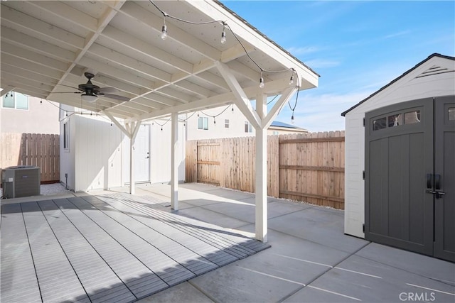 view of patio / terrace with an outbuilding, ceiling fan, a fenced backyard, central air condition unit, and a storage unit