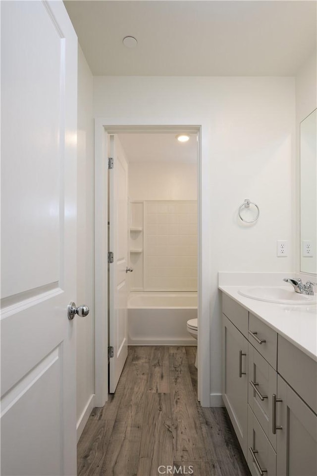 full bathroom with toilet,  shower combination, wood finished floors, and vanity