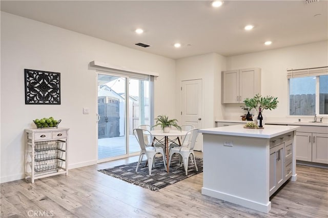 kitchen featuring light countertops, a kitchen island, visible vents, and light wood-style floors