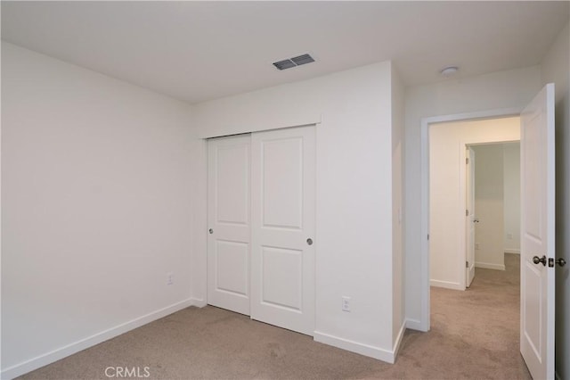 unfurnished bedroom with baseboards, a closet, visible vents, and light colored carpet