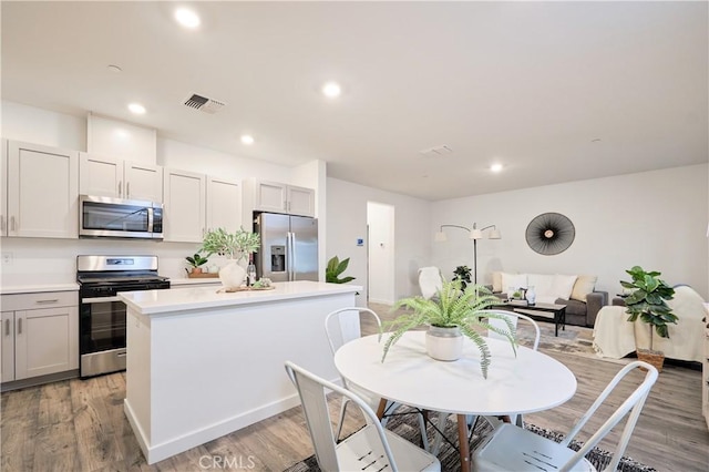 kitchen with light wood-style flooring, visible vents, stainless steel appliances, and a center island