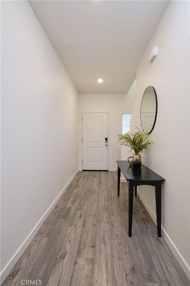 corridor featuring light wood finished floors, baseboards, and recessed lighting