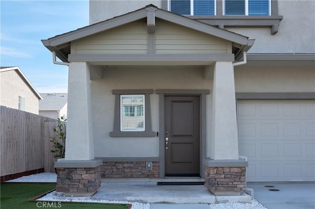 property entrance featuring stone siding, fence, and stucco siding