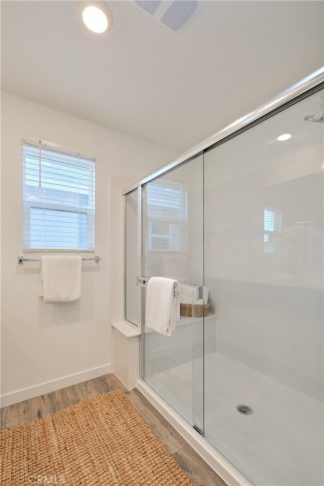 bathroom with a stall shower, wood finished floors, visible vents, and baseboards