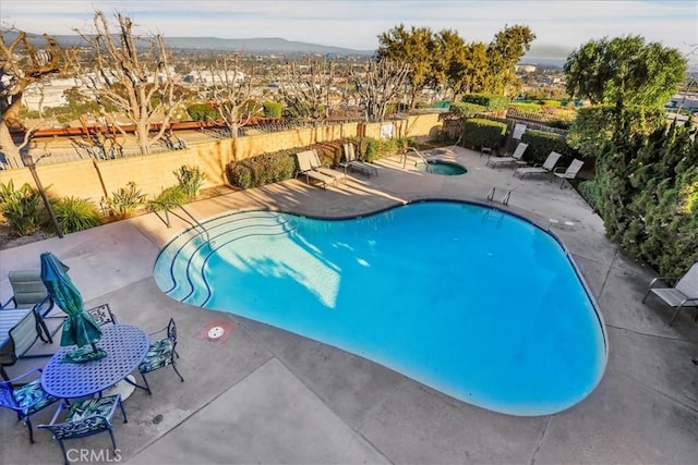 pool with fence, a community hot tub, and a patio