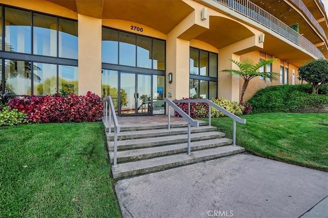 view of exterior entry featuring stucco siding and a yard