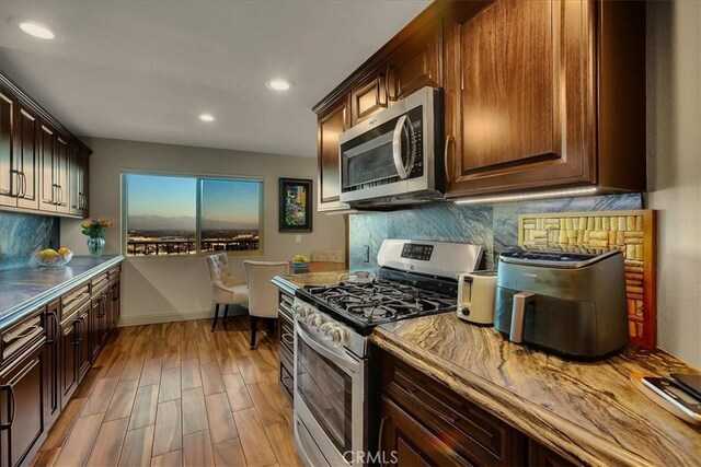 kitchen with baseboards, decorative backsplash, appliances with stainless steel finishes, light wood-type flooring, and recessed lighting