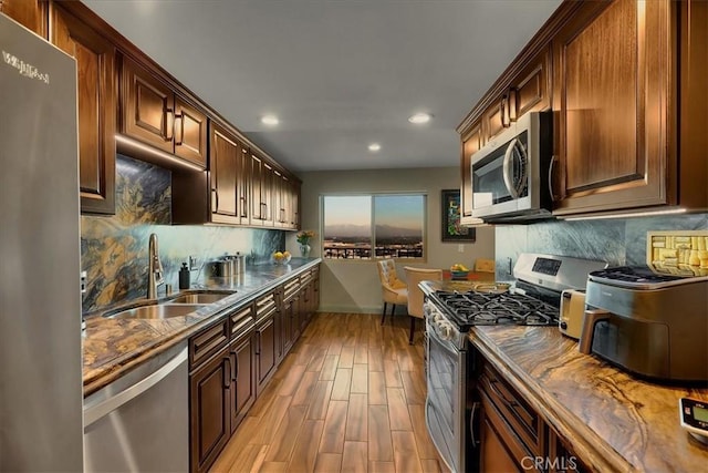 kitchen with light wood-style flooring, recessed lighting, stainless steel appliances, a sink, and tasteful backsplash