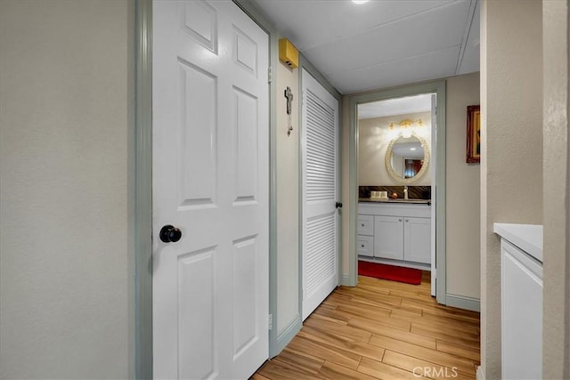 corridor featuring light wood-style flooring and baseboards