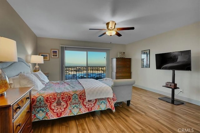 bedroom featuring access to exterior, a ceiling fan, baseboards, and light wood-style floors