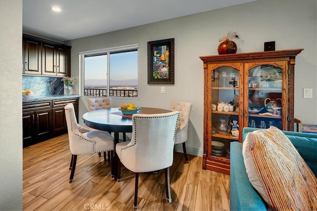 dining space with light wood-type flooring and baseboards