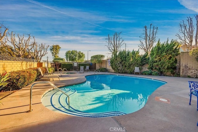 community pool with a patio and a fenced backyard