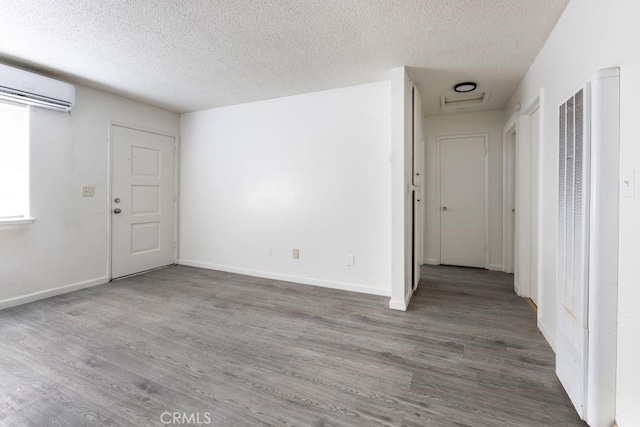 unfurnished room with wood finished floors, a heating unit, a textured ceiling, and a wall mounted AC