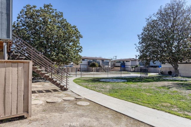 view of home's community featuring a residential view, fence, a lawn, and stairs