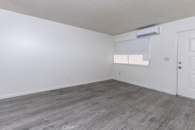 empty room featuring baseboards, an AC wall unit, and wood finished floors