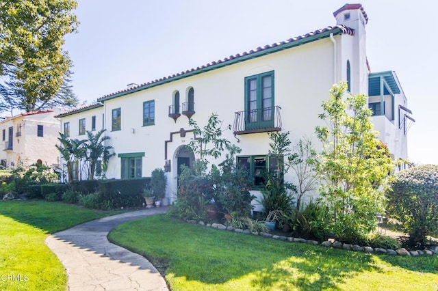 mediterranean / spanish house with a chimney, a front lawn, and stucco siding