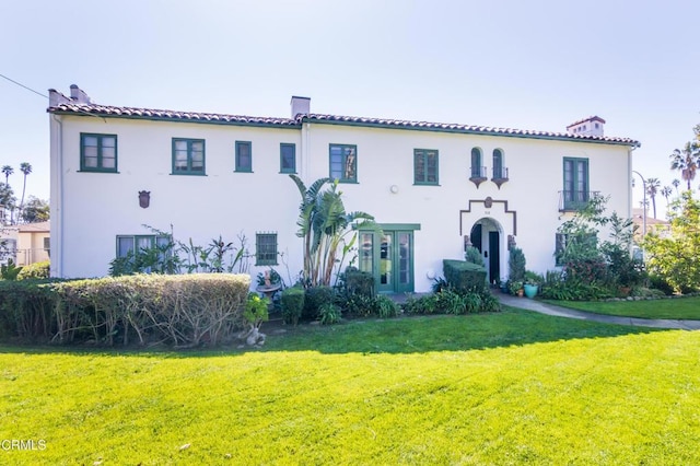 mediterranean / spanish-style house with a chimney, a front lawn, and stucco siding