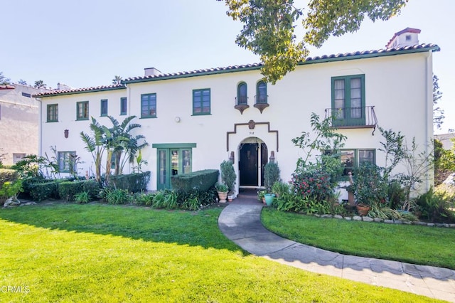 mediterranean / spanish-style home with a tiled roof, a front yard, and stucco siding