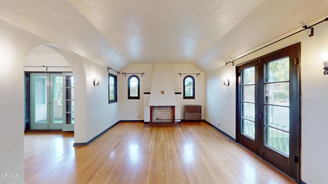 empty room with arched walkways, wood finished floors, and french doors