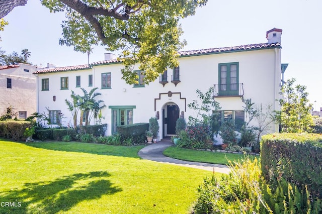 mediterranean / spanish home featuring stucco siding, a tile roof, and a front yard