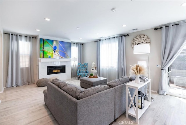 living area with light wood-style floors, a high end fireplace, visible vents, and recessed lighting