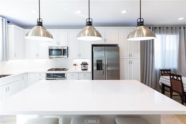 kitchen with light countertops, appliances with stainless steel finishes, white cabinets, and tasteful backsplash