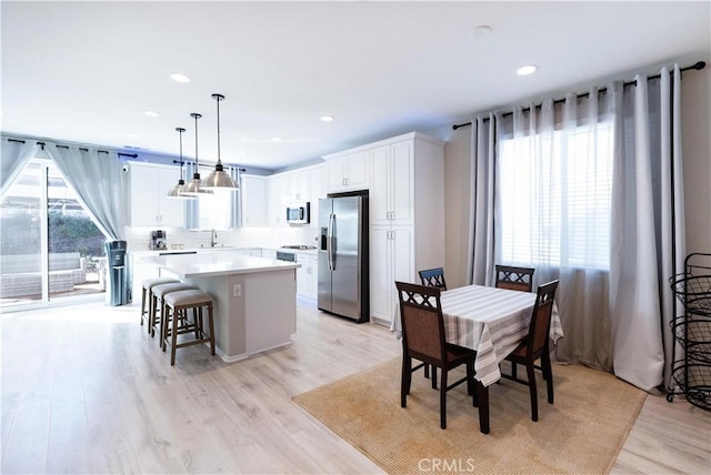 kitchen featuring light wood finished floors, white cabinetry, stainless steel appliances, and a center island