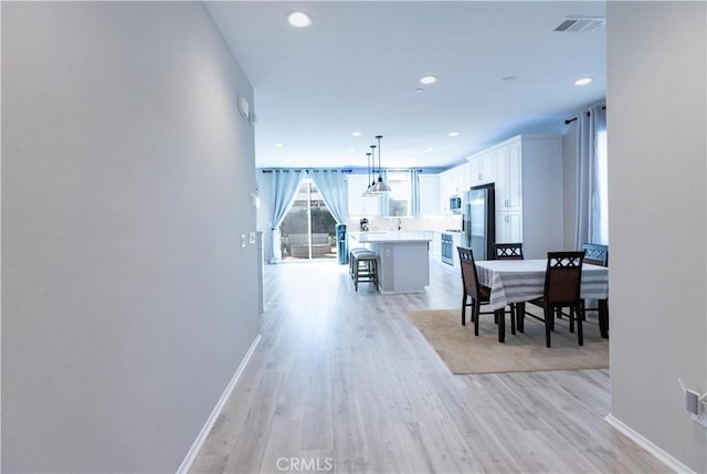 hallway with light wood finished floors, baseboards, and recessed lighting