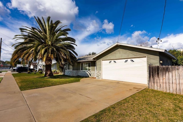 view of front of property featuring an attached garage, fence, driveway, stucco siding, and a front yard