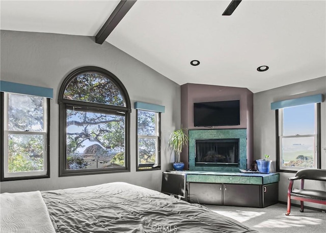 carpeted bedroom featuring lofted ceiling with beams, multiple windows, and a fireplace