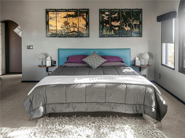 bedroom featuring carpet, arched walkways, and baseboards