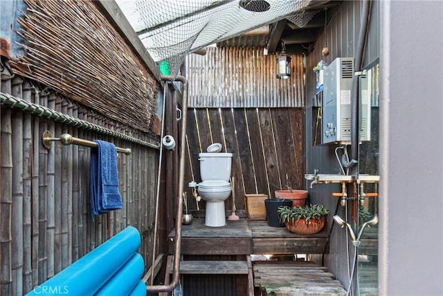 bathroom featuring toilet, wood walls, and water heater