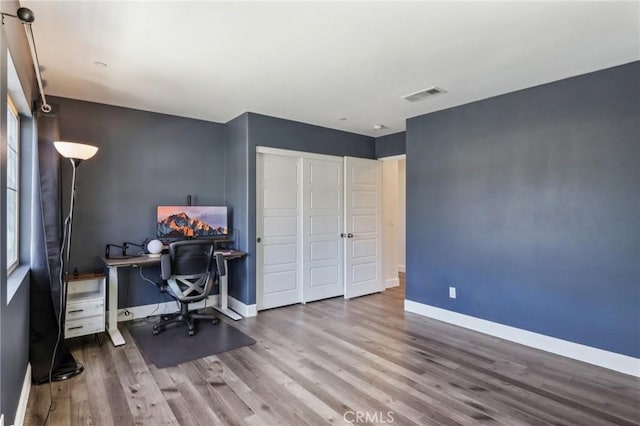 office space featuring baseboards, visible vents, and wood finished floors