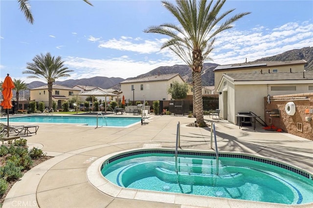 pool featuring a patio, a community hot tub, fence, and a mountain view