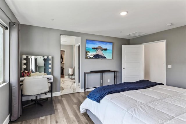 bedroom with visible vents, baseboards, and wood finished floors