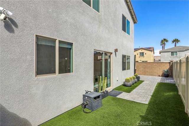 back of house with a yard, a fenced backyard, a patio area, and stucco siding