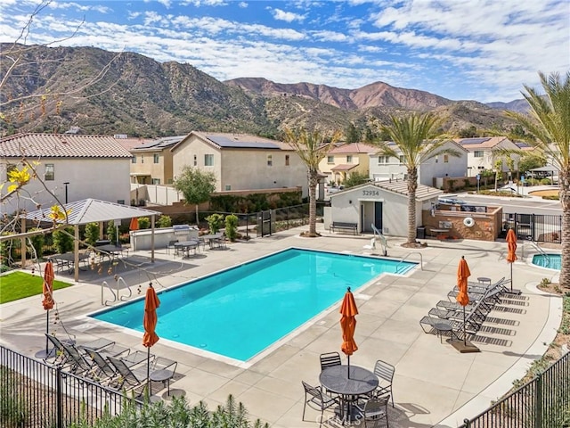 community pool with a residential view, fence, a mountain view, and a patio