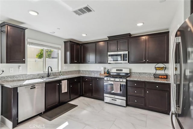 kitchen featuring visible vents, marble finish floor, stainless steel appliances, dark brown cabinets, and a sink