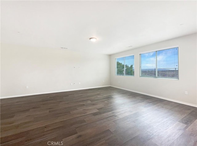 empty room featuring dark wood-style floors and baseboards