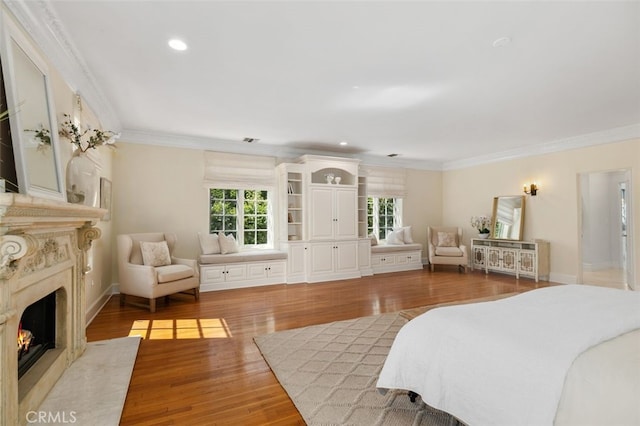 bedroom with crown molding, recessed lighting, visible vents, a premium fireplace, and wood finished floors