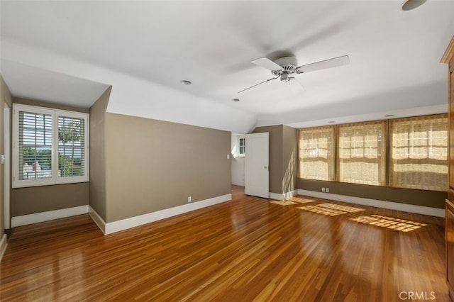 interior space with a ceiling fan, vaulted ceiling, baseboards, and wood finished floors