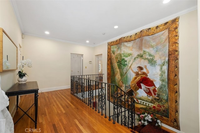 corridor with an upstairs landing, crown molding, baseboards, and wood finished floors